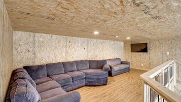 A room with a sectional sofa, wooden flooring, and a television mounted on the wall.