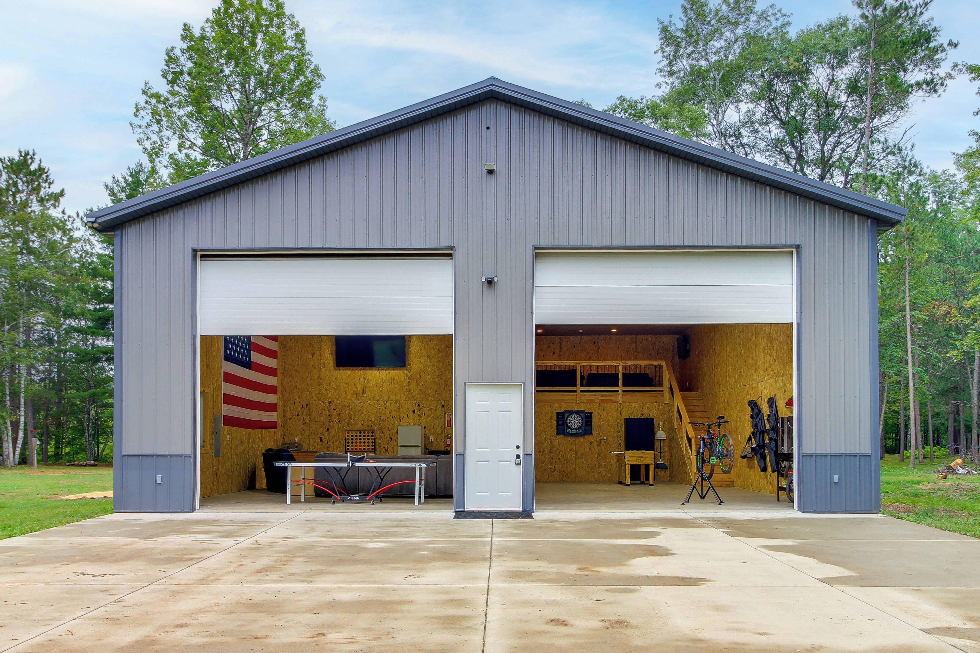 A two-story metal building with a garage door, a table, and a dartboard.