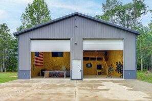A two-story metal building with a garage door, a table, and a dartboard.