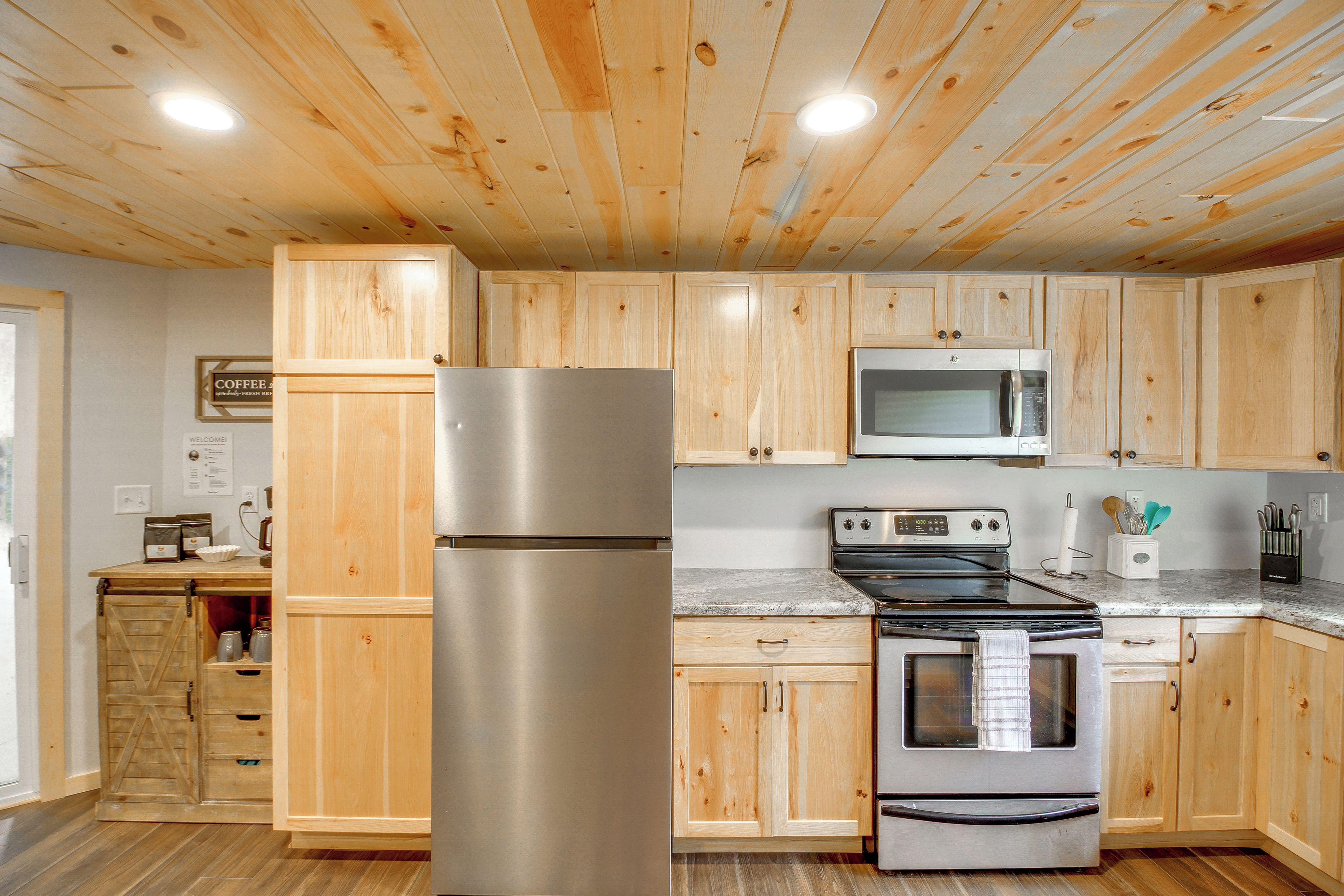 A kitchen with wooden cabinets, stainless steel appliances, and a marble countertop.