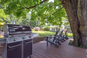 Eine Terrasse mit einem Weber Genesis Grill, Sitzgelegenheiten im Freien und einem Holzboden.