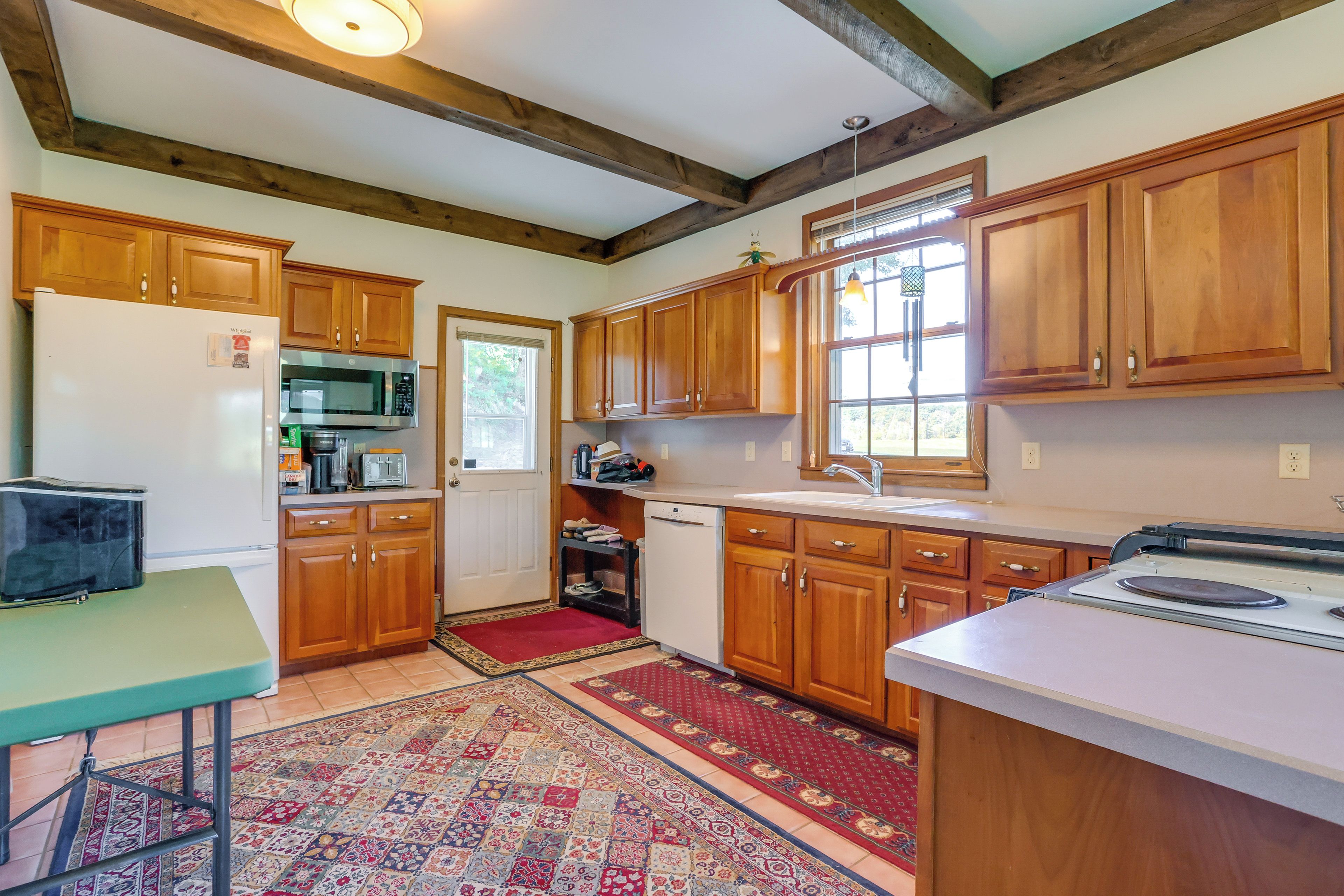A kitchen with wooden cabinets, a microwave, a refrigerator, and a sink.