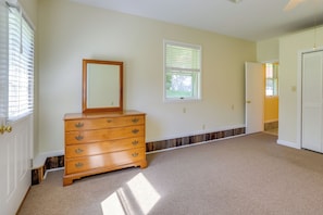 A room with a wooden dresser, two windows with blinds, a door, and a carpeted floor. - On-site Ponds! Peaceful Franklin Studio (Franklin)