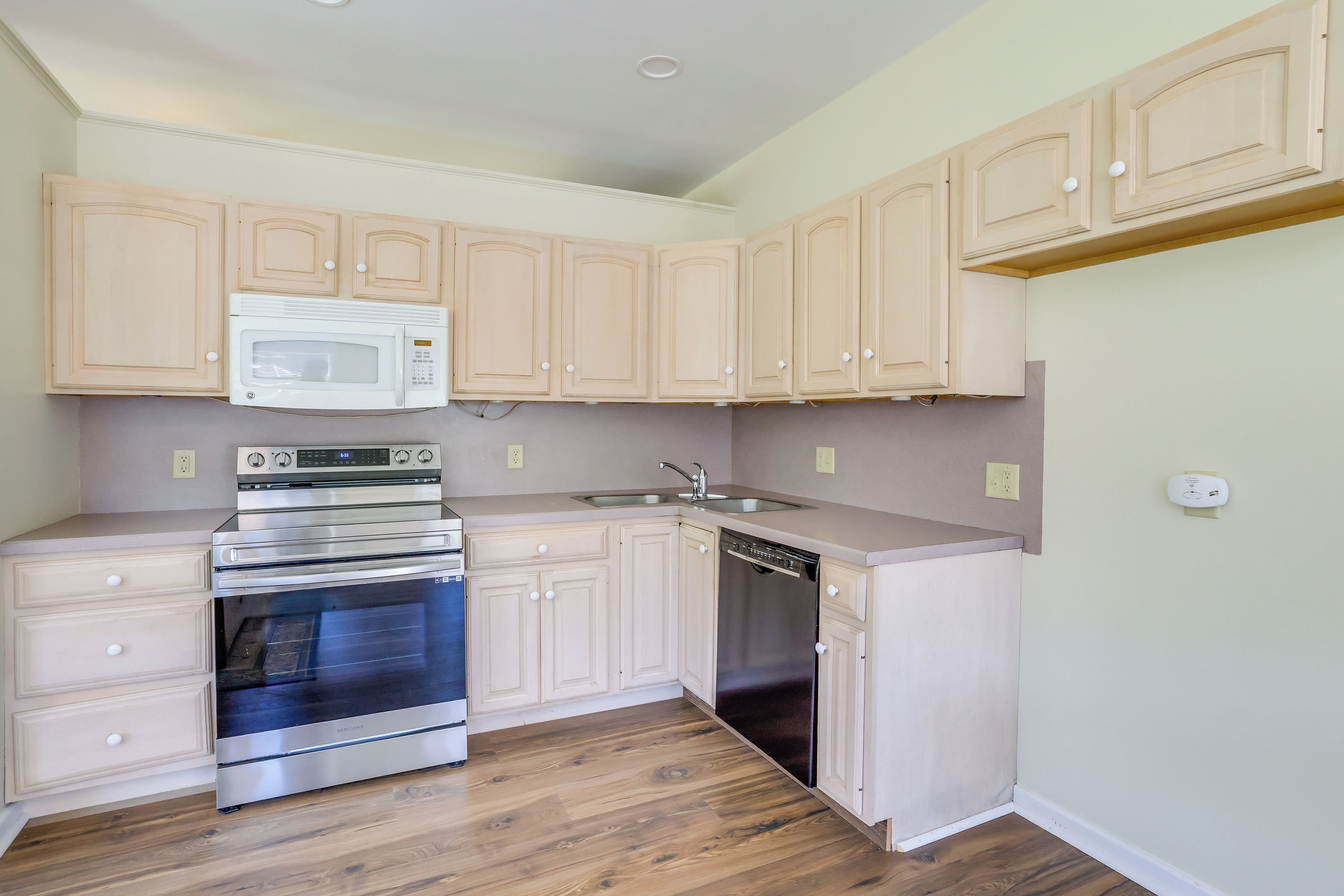 A kitchen with wooden cabinets, a microwave, an oven, and a dishwasher.