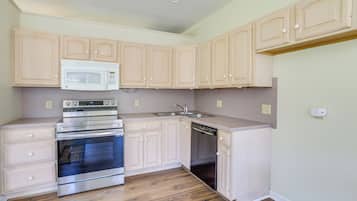A kitchen with wooden cabinets, a microwave, an oven, and a dishwasher.