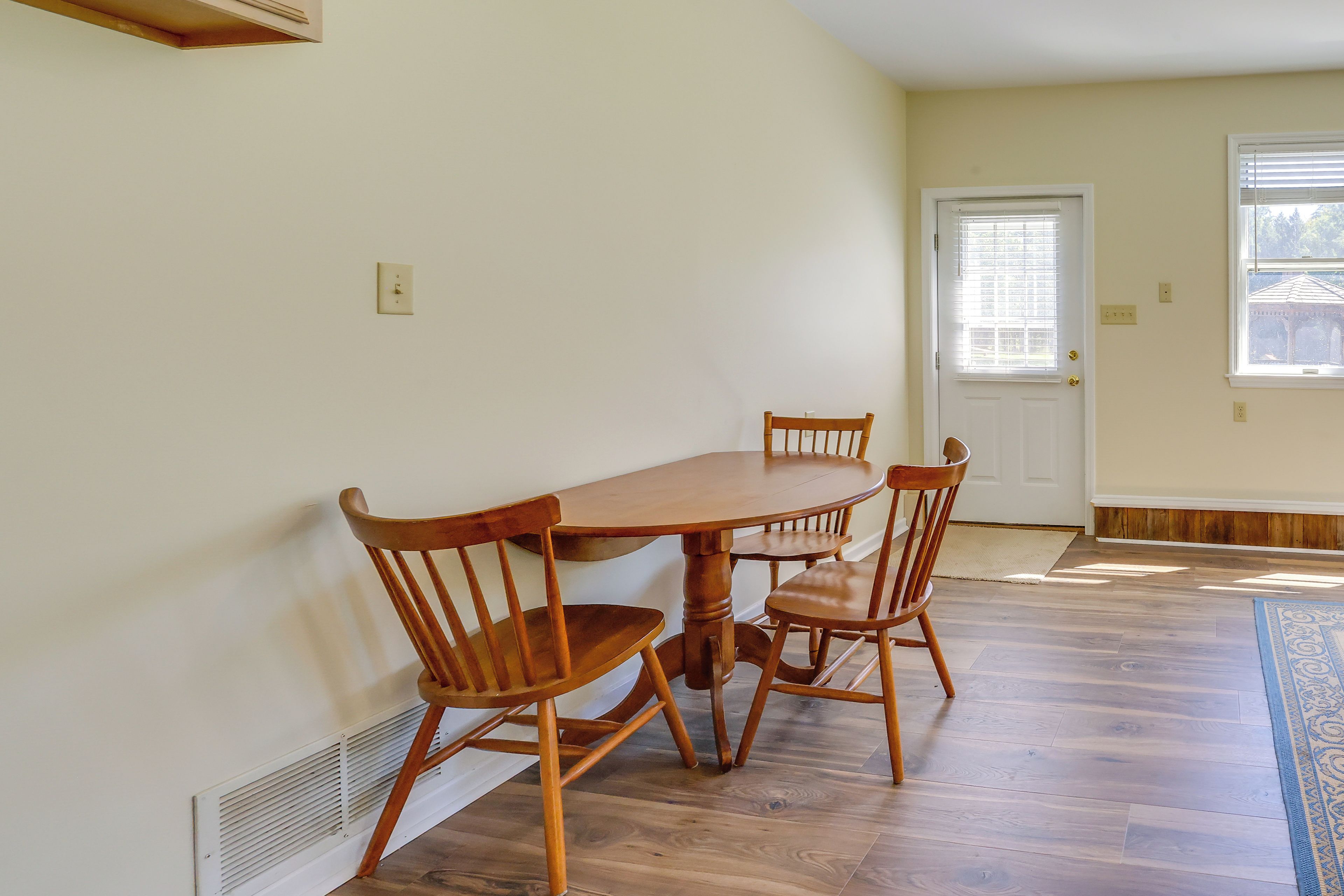 A dining area with a wooden table and chairs, a white door, and a window with blinds.
