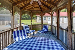 A covered porch with a checkered tablecloth, striped chairs, and a ceiling fan. - On-site Ponds! Peaceful Franklin Studio (Franklin)