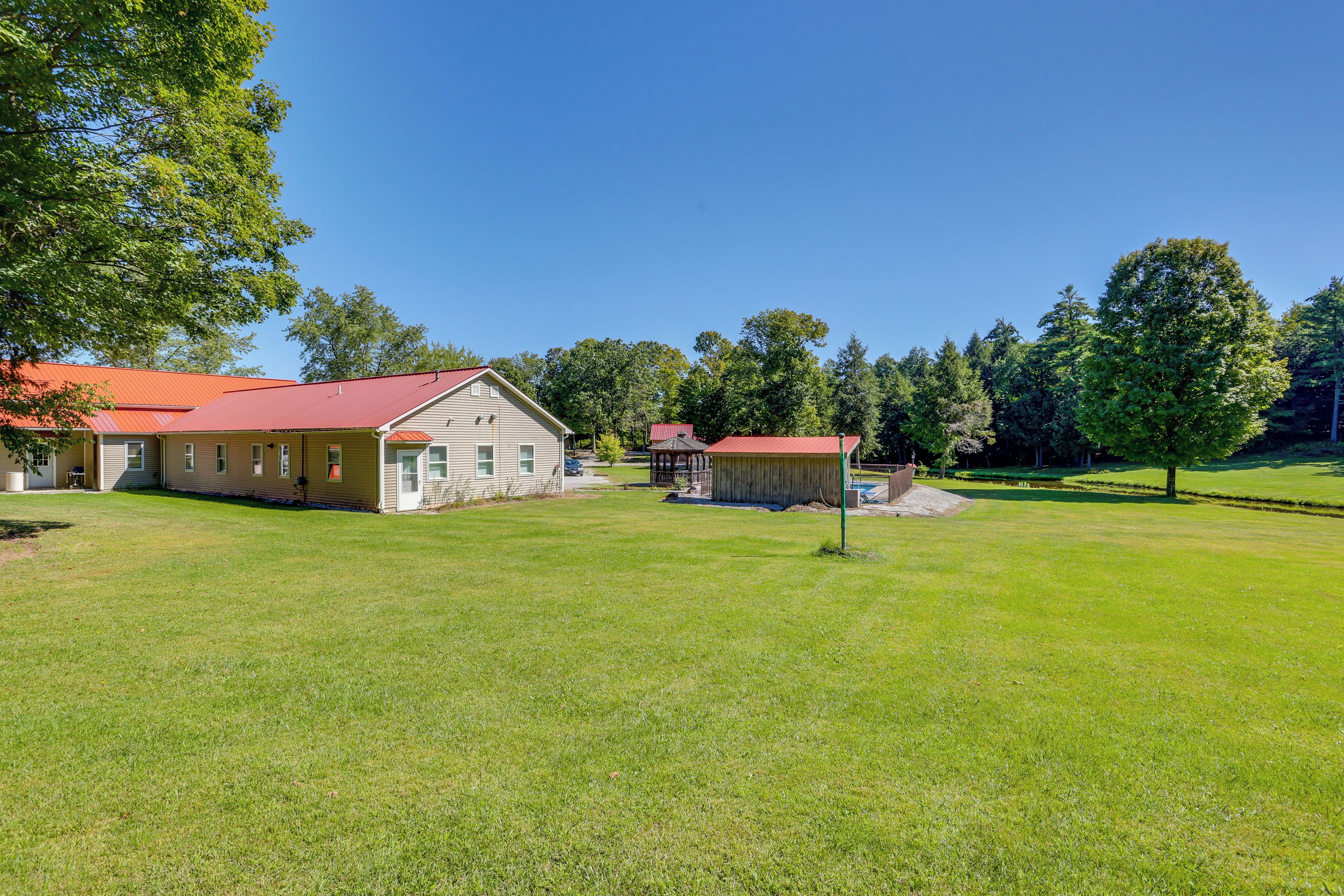 A residential property with a large lawn, a main house, and a smaller building, possibly a garage or shed, under a clear sky.