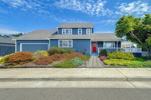 A two-story house with a red front door, a garage, and a well-maintained front yard with various shrubs and flowers. - 2 Mi to Ocean & Coastal Trails! Mckinleyville Home (McKinleyville)