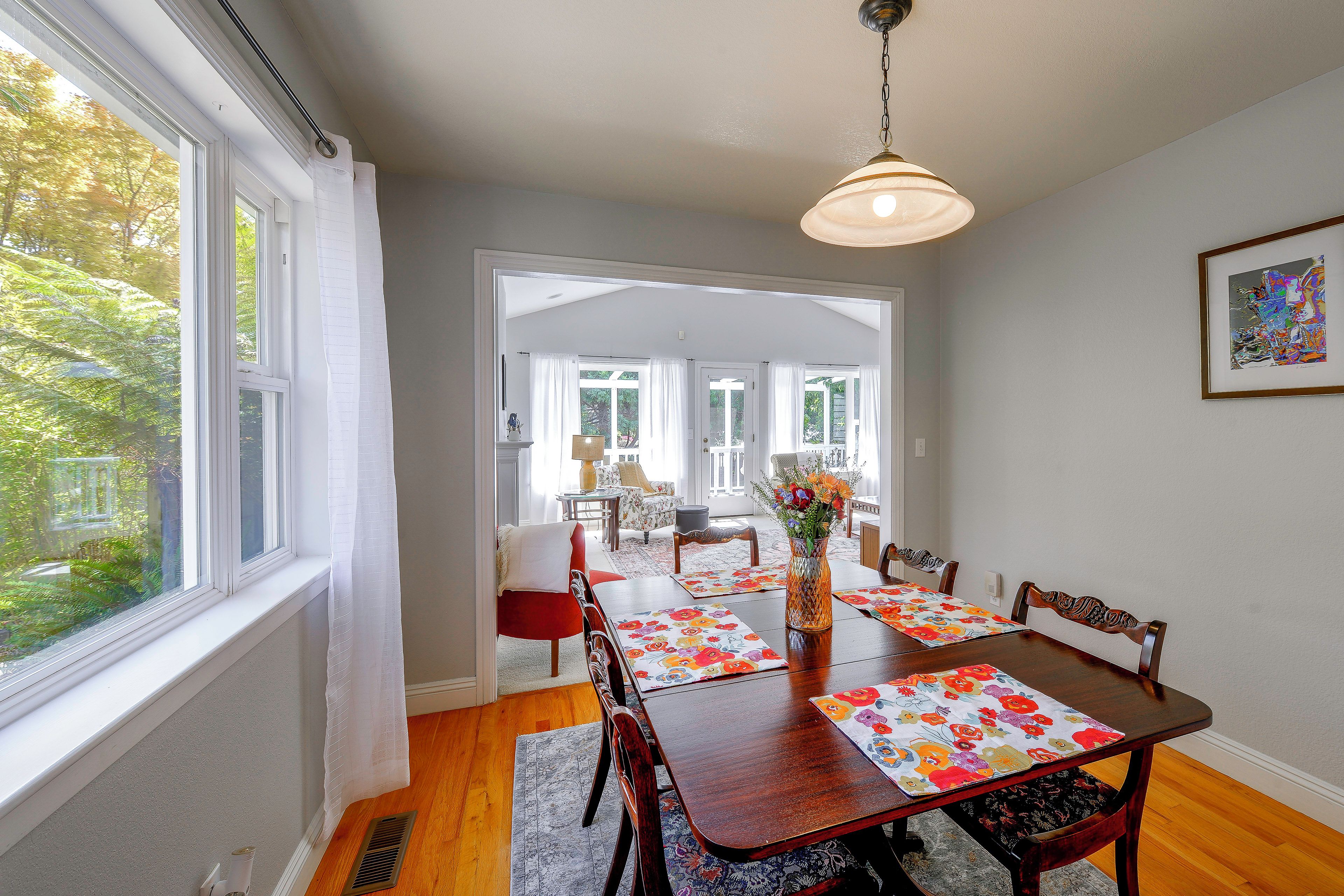 A dining area with a wooden table, chairs, and a vase of flowers.