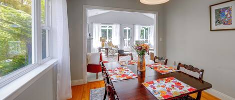 A dining area with a wooden table, chairs, and a vase of flowers.