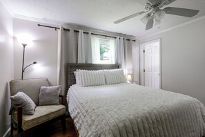A bedroom with a bed, a chair, a ceiling fan, and a window with curtains. - Hickory Haven w/ Home Gym & Quiet Backyard Porch (Hickory)