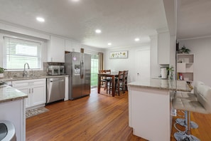 A modern kitchen with white cabinetry, stainless appliances, and a wooden floor. - Hickory Haven w/ Home Gym & Quiet Backyard Porch (Hickory)