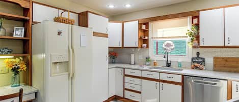 A kitchen with white cabinets, a stainless steel dishwasher, and a water dispenser.