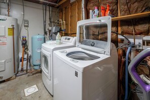 A laundry room with a front-loading washer and dryer, a water heater, and various plumbing pipes. - Valley Retreat Near Massanutten & Harrisonburg (Penn Laird)