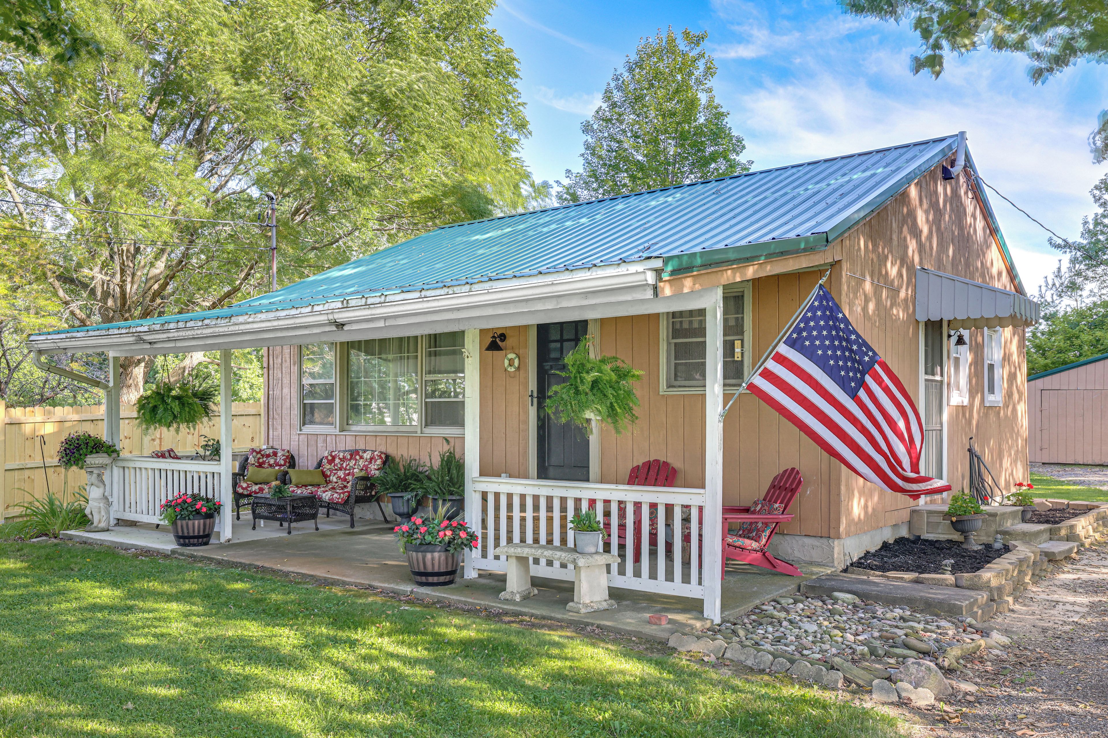 A wooden house with a porch, a covered patio, and an American flag.