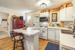 A kitchen with white cabinetry, a red refrigerator, a gas stove, and a microwave.