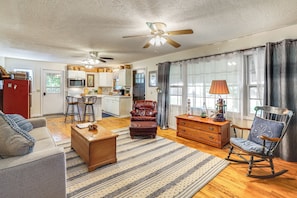 A spacious living area with a sofa, coffee table, and a rocking chair. A kitchen with a microwave and a ceiling fan is visible in the background. - 3 Bicycles & Peek-a-boo Lake Views! Barker Gem (Barker)