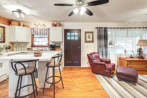 A kitchen with a central island, bar stools, a dark wooden door, and a living area with a leather chair and ottoman. - 3 Bicycles & Peek-a-boo Lake Views! Barker Gem (Barker)