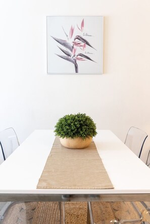 A dining table with a potted plant in the center, a framed botanical illustration on the wall, and a clear view of the table's edge. - Cozy Studio CBD Stay Next to Darling Harbour (Sydney)