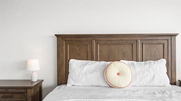 A bedroom with a wooden headboard, a white bedspread, and a bedside table with a lamp.