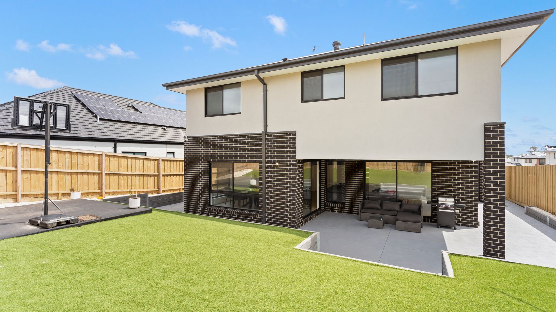 A modern two-story house with a flat roof, a brick exterior, and a well-maintained lawn.