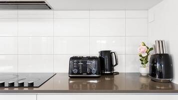 A kitchen with a black radio, a black coffee maker, and a black electric kettle on the counter.