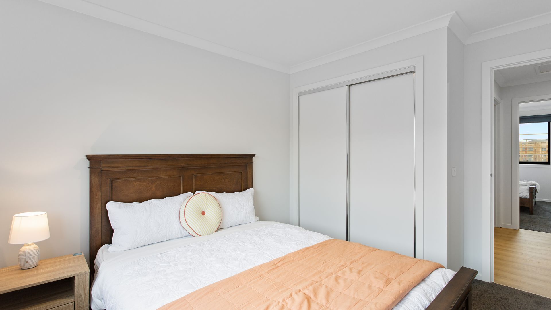 Una camera d'albergo con un letto, un comodino, una lampada e un armadio.