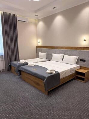 Habitació d'hotel amb un llit doble, una taula de nit i un aire condicionat.