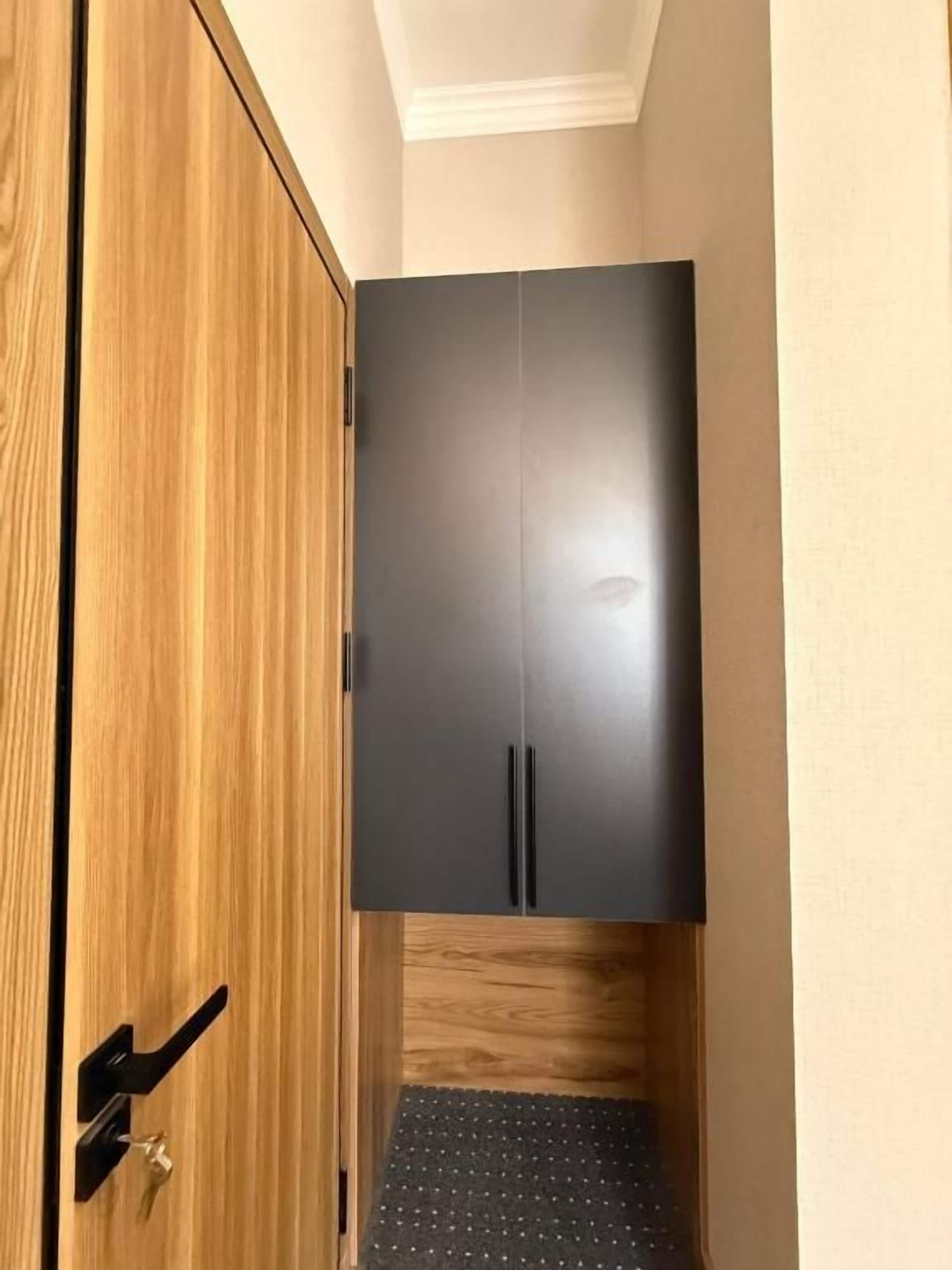 A room with a wooden wardrobe and a black cabinet.