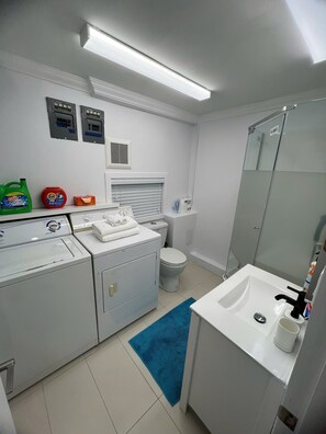 A compact, modern bathroom with a washing machine, a toilet, a sink, and a mirror. - Clean Spacious Vancouver home - Nanaimo skytrain - Trout Lake (Vancouver)