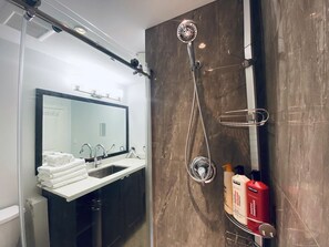 A modern bathroom with a glass-enclosed shower, a sink with a mirror, and toiletries. - Clean Spacious Vancouver home - Nanaimo skytrain - Trout Lake (Vancouver)