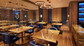 Un restaurante con varias mesas y sillas, una pared de ladrillo y una lámpara moderna.