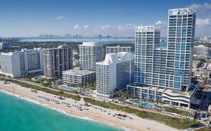 A coastal cityscape with high-rise buildings, a beach, and a clear view of the city skyline in the distance.