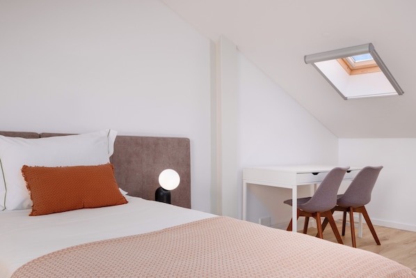 Une chambre à coucher avec un lit, un bureau et deux chaises.