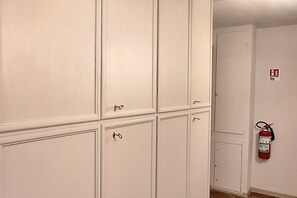 A room with white cabinets, a fire extinguisher mounted on the wall, and a door with a fire alarm sticker. - Casa Mimosa is a typical old Florentine apartment, designed for the relaxation of our guests, we are in the lively central district Oltrarno.At Casa Mimosa you can find a kitchen living room with sofa bed and study corner, a bedroom with double bed, a ba (Florence)