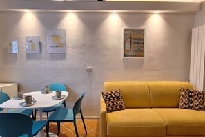 A dining area with a round table, chairs, and a yellow sofa with patterned cushions. - Casa Mimosa is a typical old Florentine apartment, designed for the relaxation of our guests, we are in the lively central district Oltrarno.At Casa Mimosa you can find a kitchen living room with sofa bed and study corner, a bedroom with double bed, a ba (Florence)