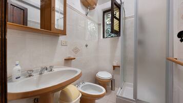 Un bagno con lavandino, bidet, toilette e cabina doccia in vetro.
