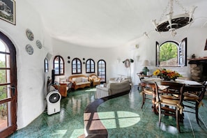 A spacious living area with a large window, a fireplace, and a dining table set for four.