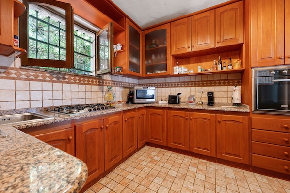 A kitchen with wooden cabinets, a gas stove, a microwave, and a refrigerator.