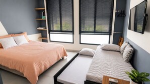 A bedroom with two beds, a window with blinds, a shelf with items, and a plant. - Acogedor ApartaSuit amoblado/de 1 dormitorio en Montería con aire acondicionado. (Montería)