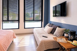 A bedroom with a bed, a sofa, a coffee table, and a TV mounted on the wall. - Acogedor ApartaSuit amoblado/de 1 dormitorio en Montería con aire acondicionado. (Montería)