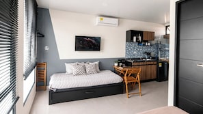 A compact bedroom with a bed, bedside table, and a small kitchenette. - Acogedor ApartaSuit amoblado/de 1 dormitorio en Montería con aire acondicionado. (Montería)