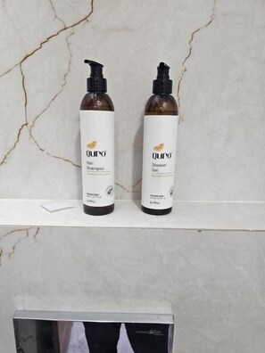 Two bottles of Qu'ro hair and shower gel on a marble shelf. - The Ushmaya Wellness Resort Rishikesh (Rishikesh)