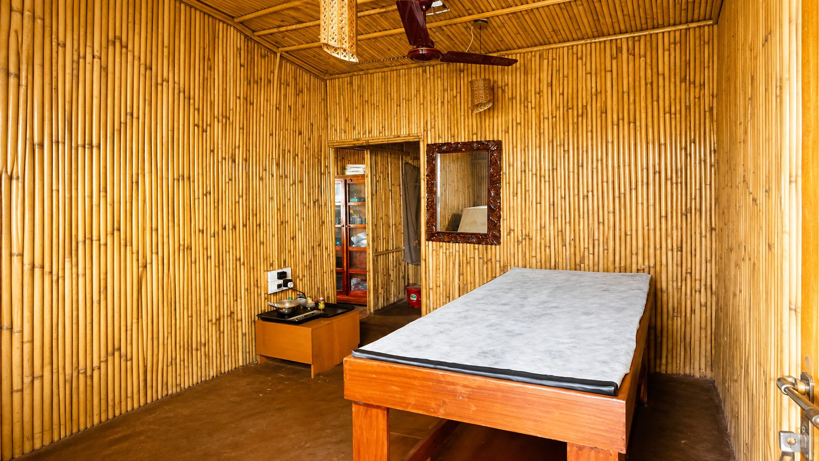 Una habitación con una cama, una mesita con utensilios de cocina y un espejo en la pared.