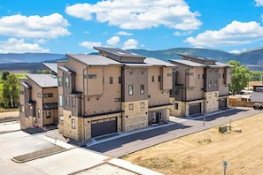 Un edificio moderno a più piani con ingresso garage, vialetto lastricato e una vista aperta sul paesaggio circostante.