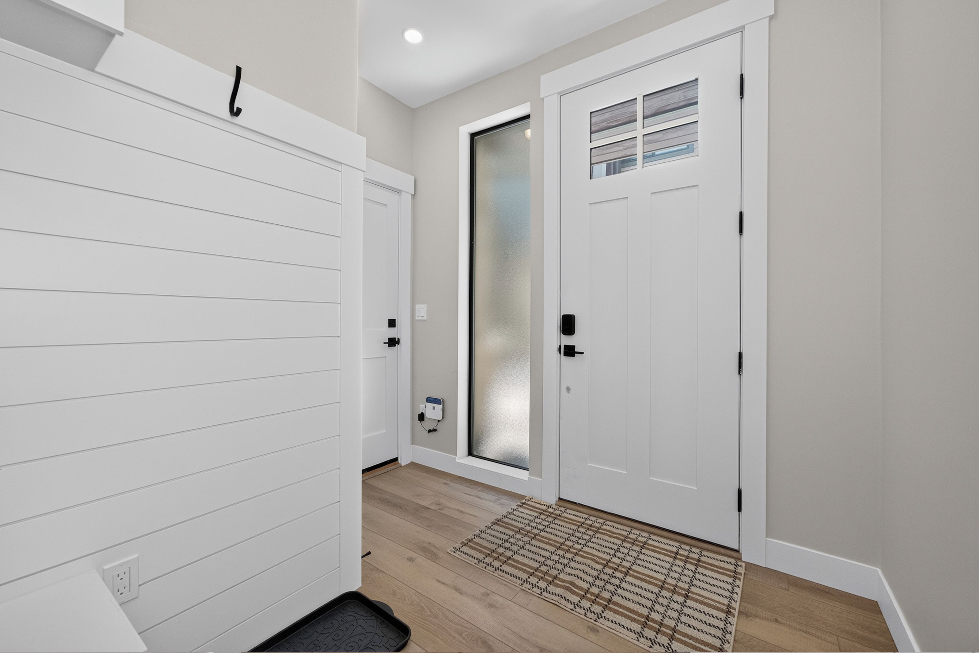A hallway with a white door, a frosted glass door, and a patterned rug on the floor.