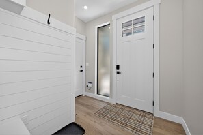 A hallway with a white door, a frosted glass door, and a patterned rug on the floor. - Granby Station Townhomes Unit 3B Rooftop deck, views, garage parking (Granby)