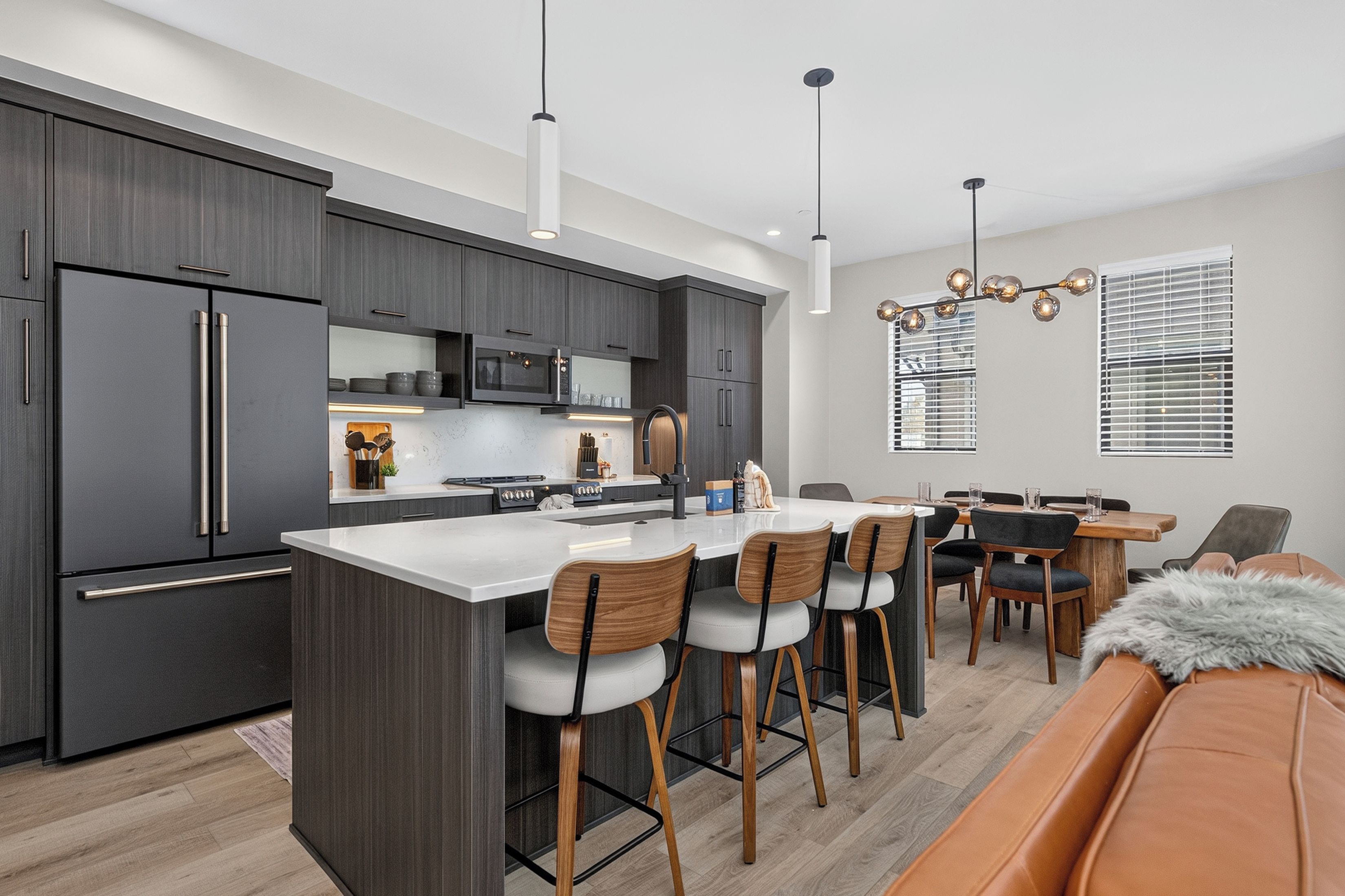 A modern kitchen with dark cabinetry, stainless steel appliances, and a central island with bar stools.