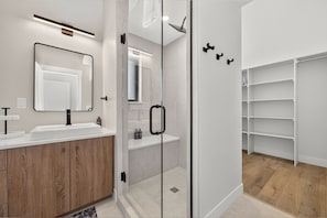 Un bagno moderno con cabina doccia in vetro, un mobile lavabo in legno e scaffali a parete.